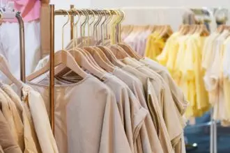 female cotton clothes in neutral colors tone hanging on clothing rack in boutique fashion store
