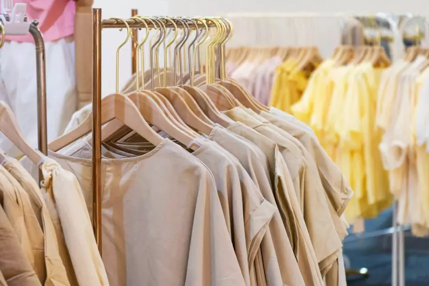 female cotton clothes in neutral colors tone hanging on clothing rack in boutique fashion store