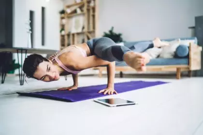 Fit girl enjoying morning yoga for training flexibility in modern home interior