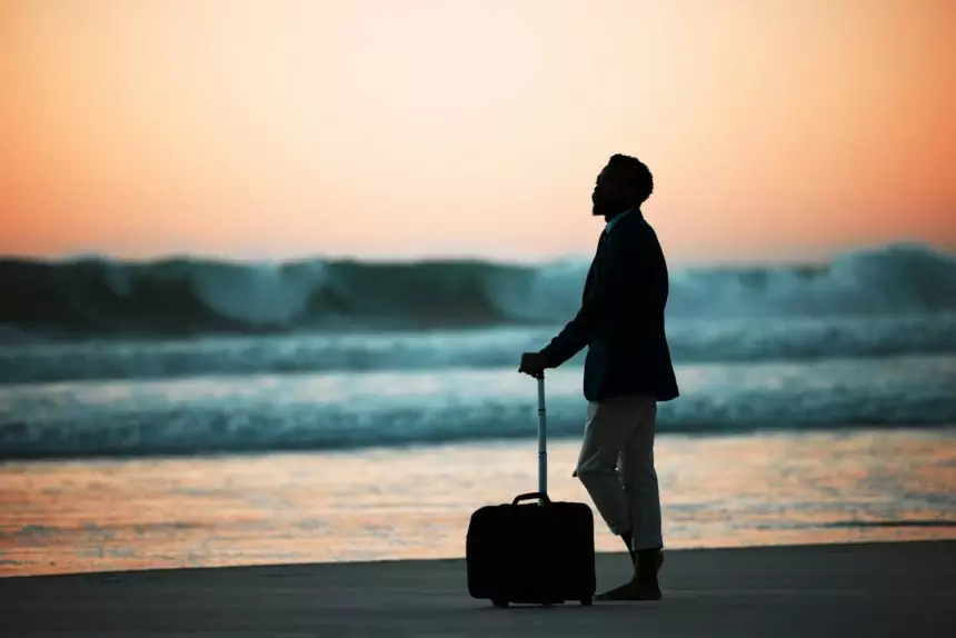 Sunset, beach and man with suitcase for travel, vacation and break in nature with freedom and solo